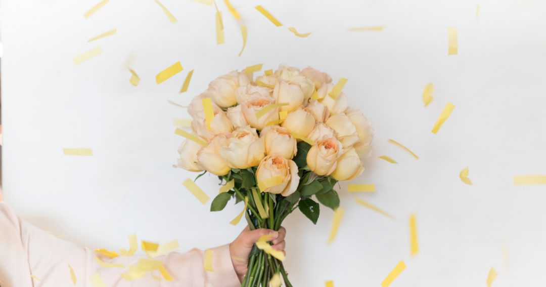 Bouquet of Peach Roses with Yellow Strips of Confetti Falling Around It