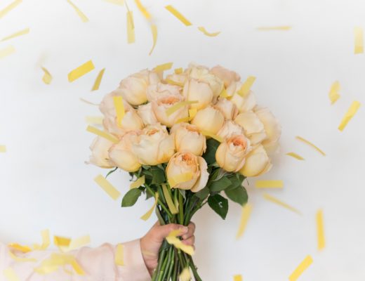 Bouquet of Peach Roses with Yellow Strips of Confetti Falling Around It
