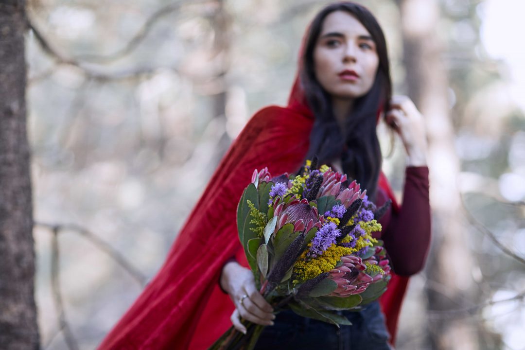 Woman wearing a red hood, holding a fall bouquet