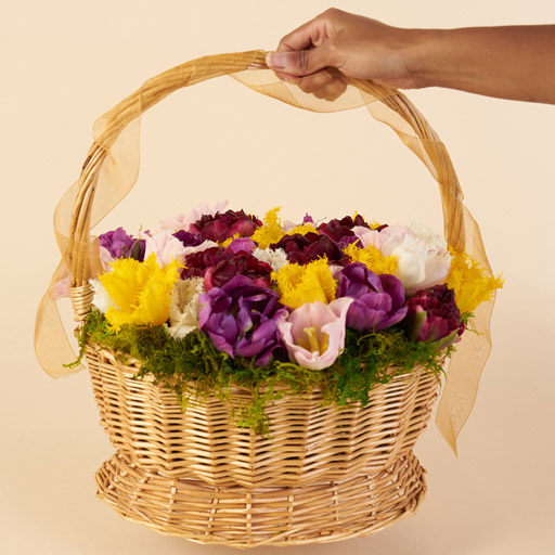 Easter basket with yellow, purple, maroon and white flowers.