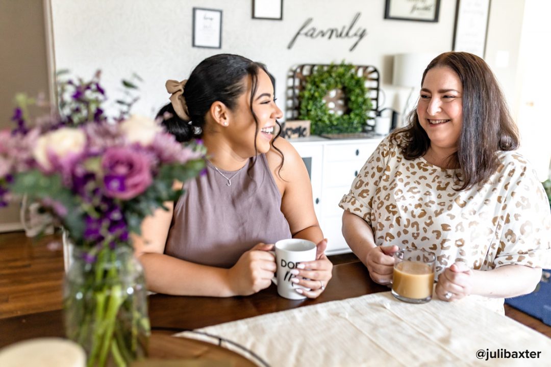 Two women having coffee with purple flowers on the table