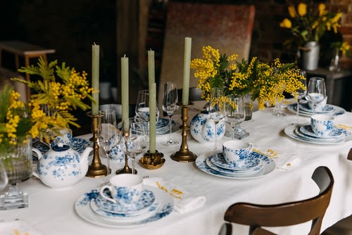 Table setting with vintage porcelain tableware, mimosa flowers and candles.