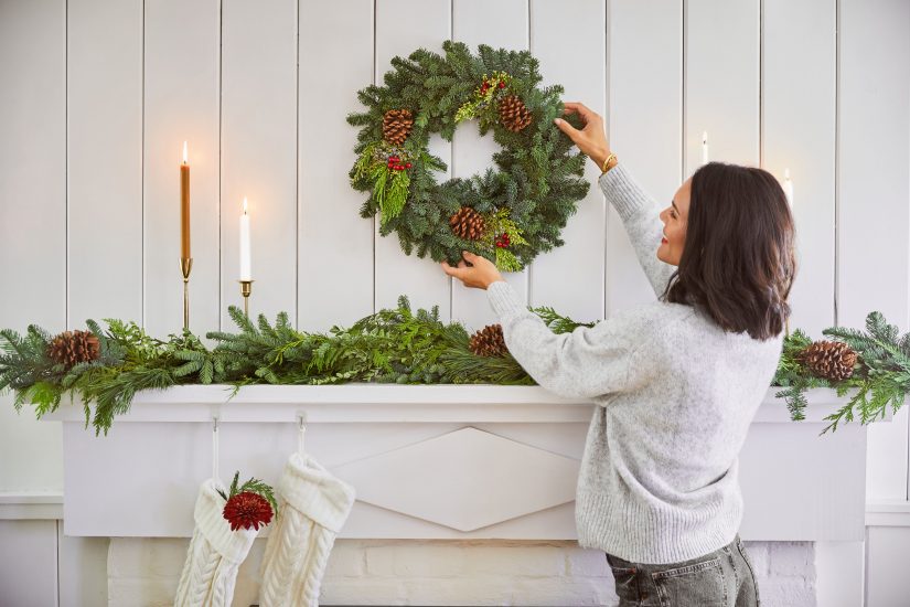 Woman placing pine wreath on the mantle