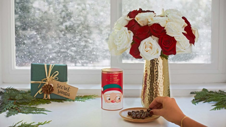 red and yellow flowers in metallic vase next to christmas treats and candies