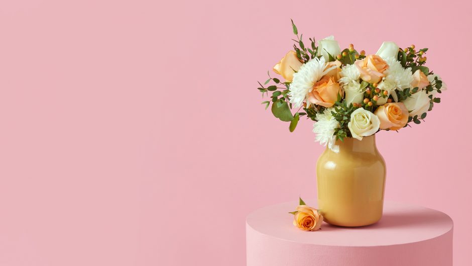 white and peach flowers in a yellow vase with a pink background