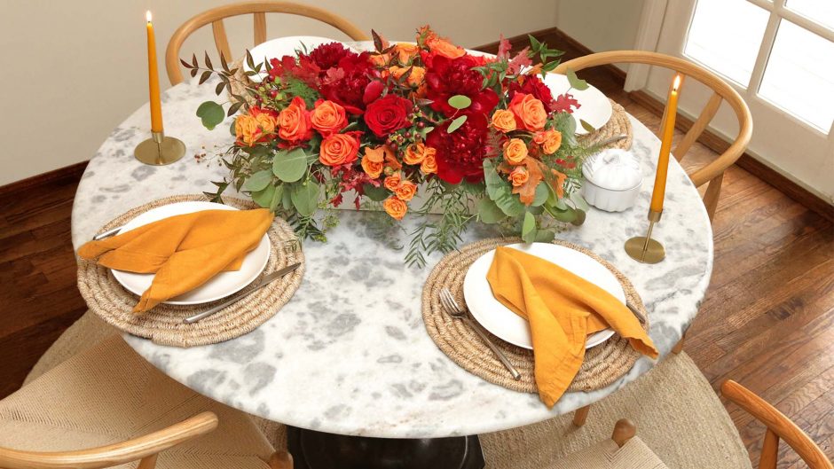 red and orange flowers on a table with orange napkins