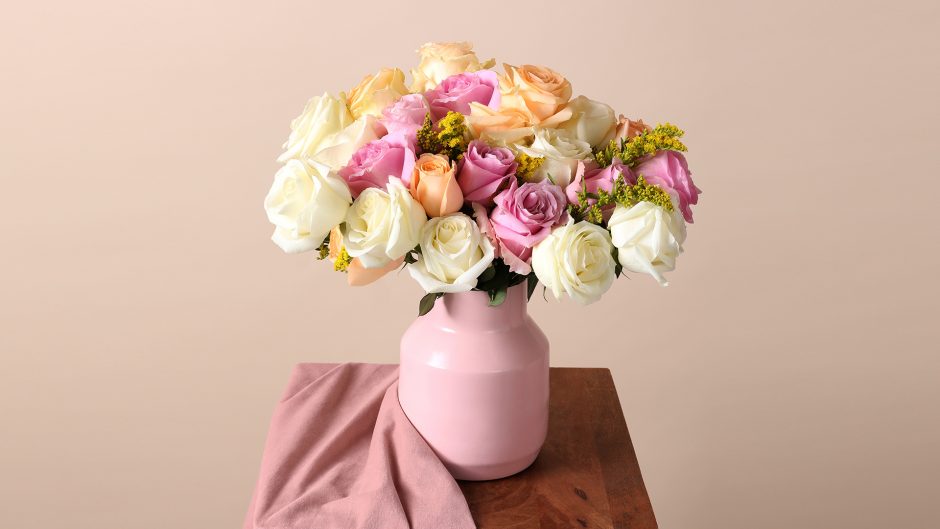 Pink, white, and peach roses in a pink vase on a wood table