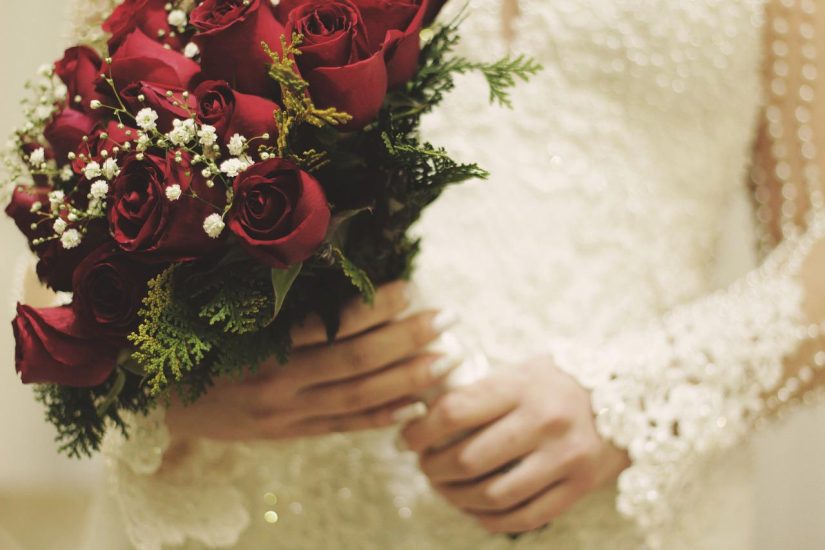 bride wearing a white wedding dress and holding a bouquet of roses