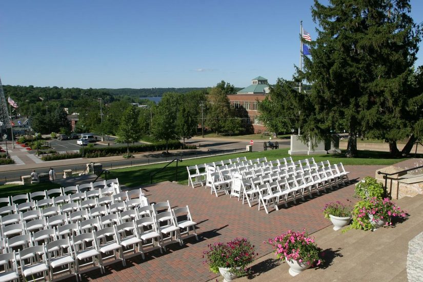 outdoor wedding venue with white folding chairs and flowers in urns