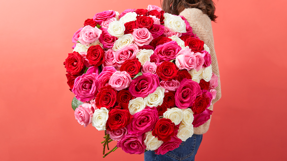 women holding 100 long stem roses in red, pink, and white