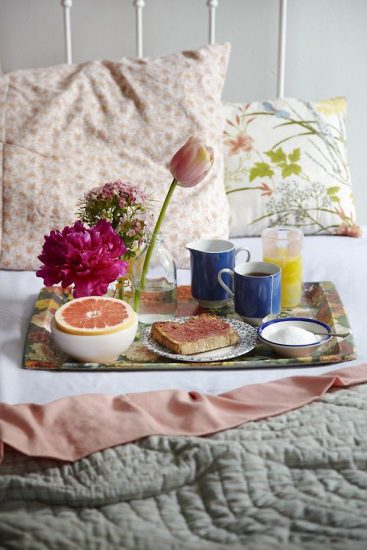 breakfast in bed on a platter with flowers in a vase