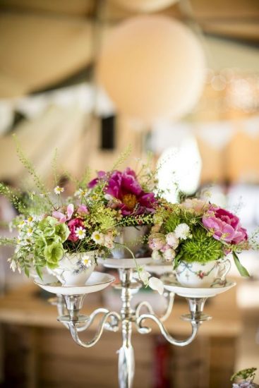 tea cups with flowers in them on a candelabra