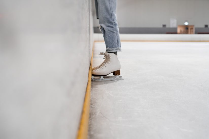 Person standing in ice skates in a skating rink