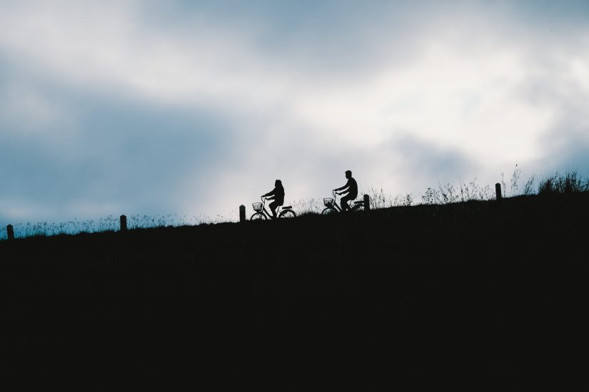 Silhouette of a couple biking across a field