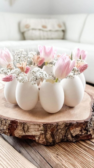 Hollowed-out easter eggs with pink flowers coming out the top