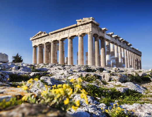 Greek Parthenon temple with yellow flowers in the foreground