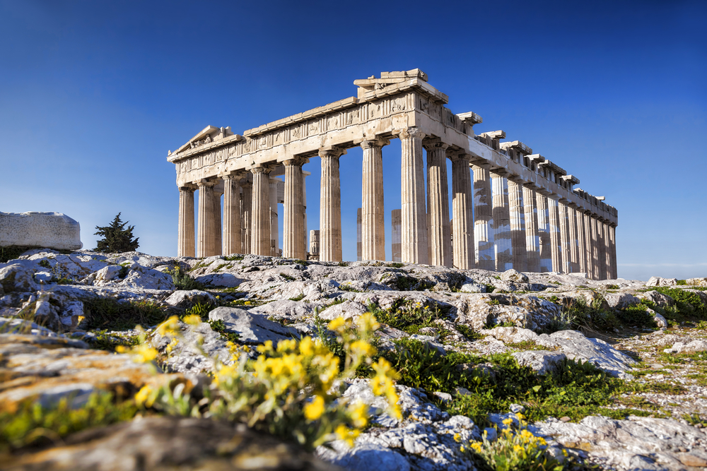 Greek Parthenon temple with yellow flowers in the foreground