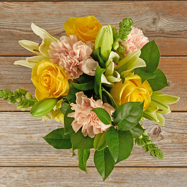 Bouquet featuring peach carnations, yellow roses and white lilies.