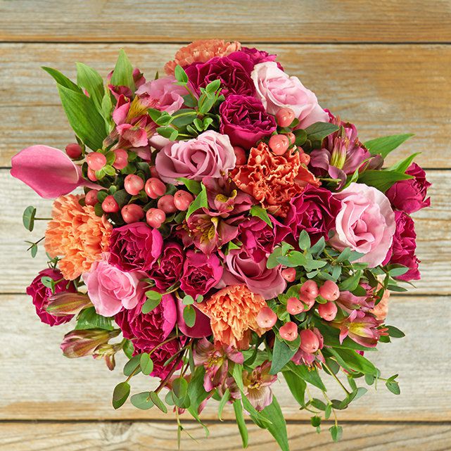 Floral arrangement featuring dark pink roses and orange carnations.