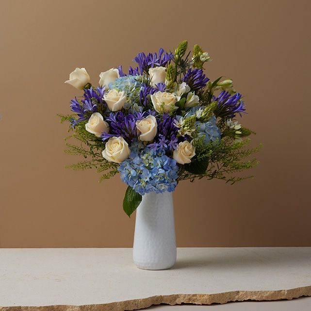 A blue bouquet in a white vase.