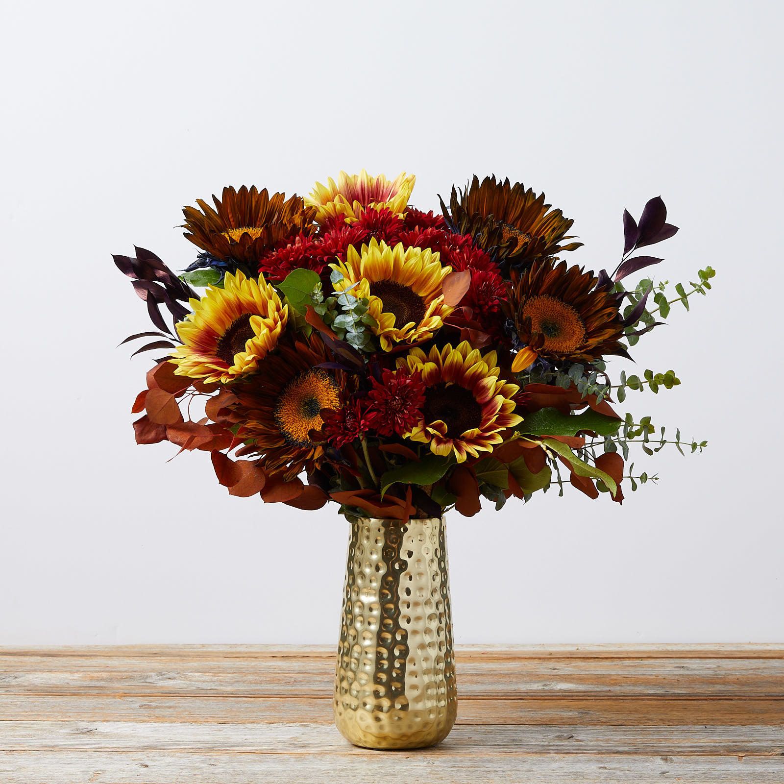 A colorful bouquet in a gold vase.