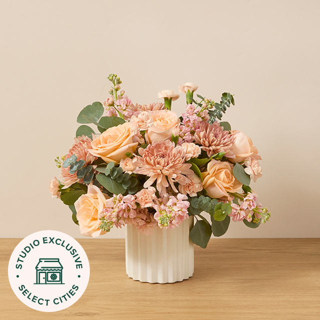 Bouquet of peach mums, roses, carnations and stock with eucalyptus.