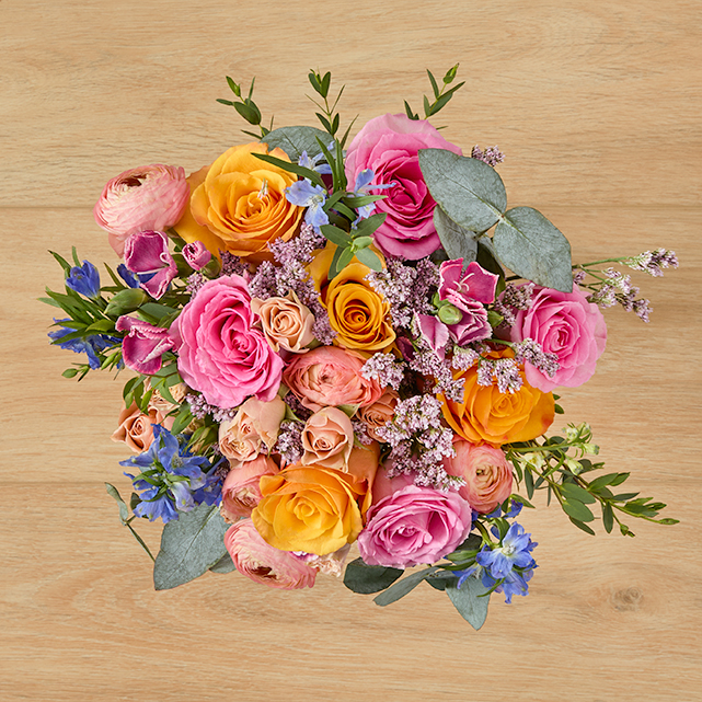 A colorful arrangement of roses, delphinium, ranunculus, and more.
