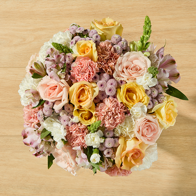 Peach and Yellow floral Bouquet with green and soft colored accent flowers.