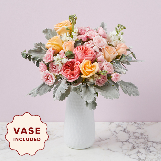 Assorted garden roses, dusty miller and a white hammered vase