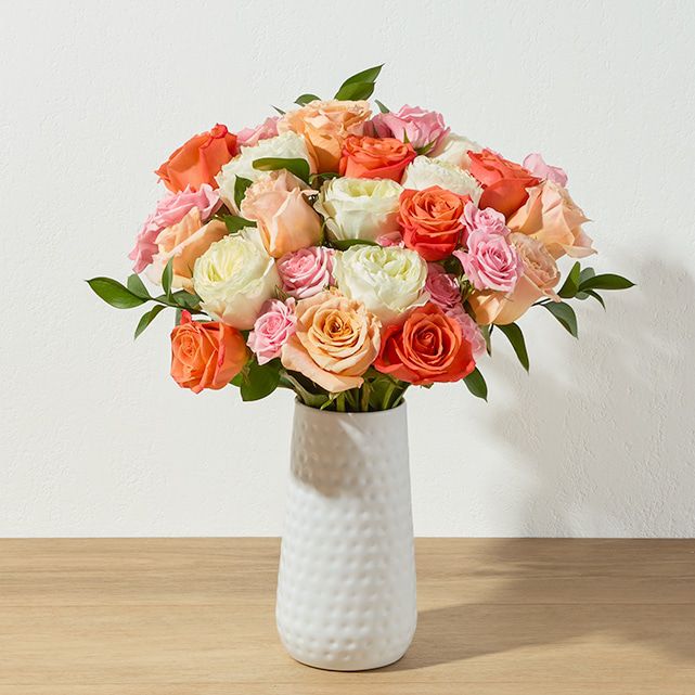 A pink and white bouquet in a white vase.