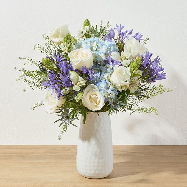 A blue and white bouquet in a white vase.