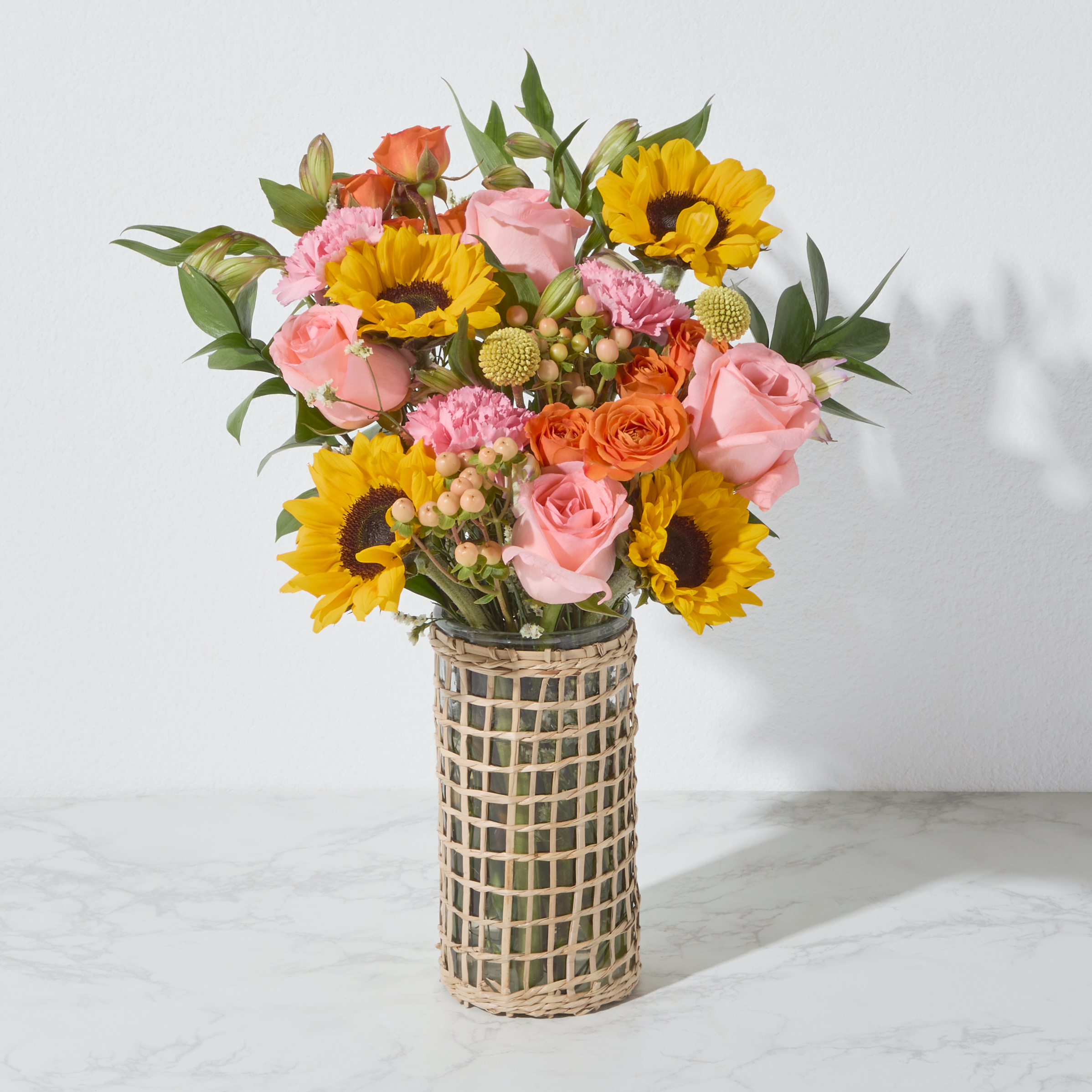 A vased arrangement of sunflowers, roses, and alstroemeria.