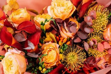 Close-up of a bundle of various fall-colored flowers in oranges, reds, and yellows.