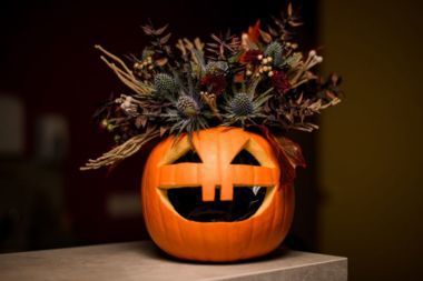Carved pumpkin with a flower bouquet arranged inside.