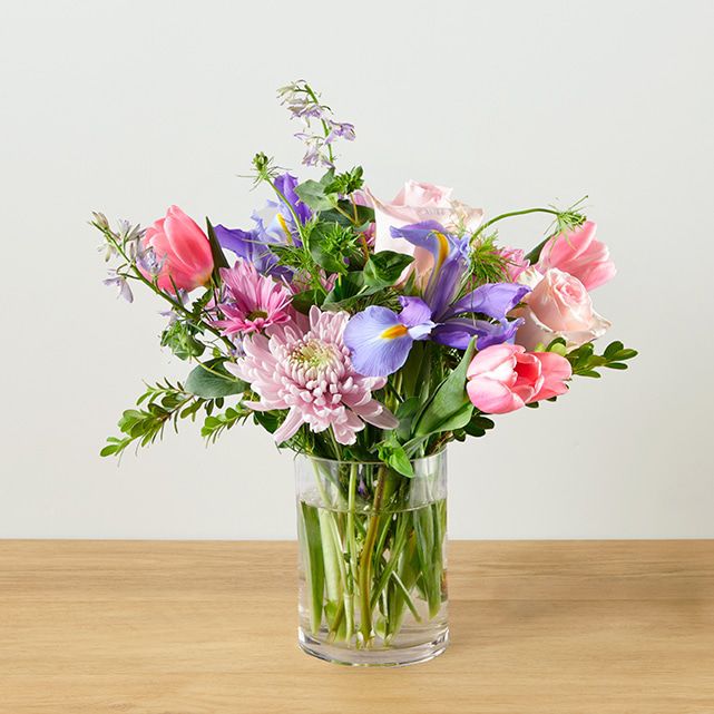 A flower arrangement in a clear vase in spring time colors.