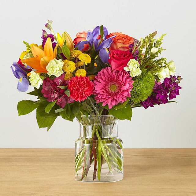 An arrangement in a clear vase featuring hot pink, orange, purple and yellow blooms.