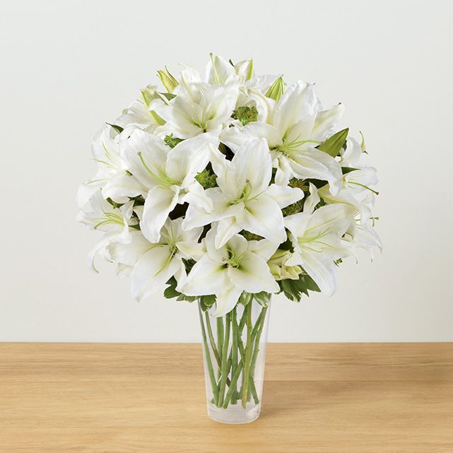 A clear vase arrangement with white lilies.