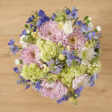 A colorful flower bouquet of green hydrangea, blue delphinium, and pink cremons.