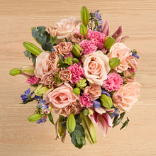 Pink lilies and roses with blue delphinium accents
