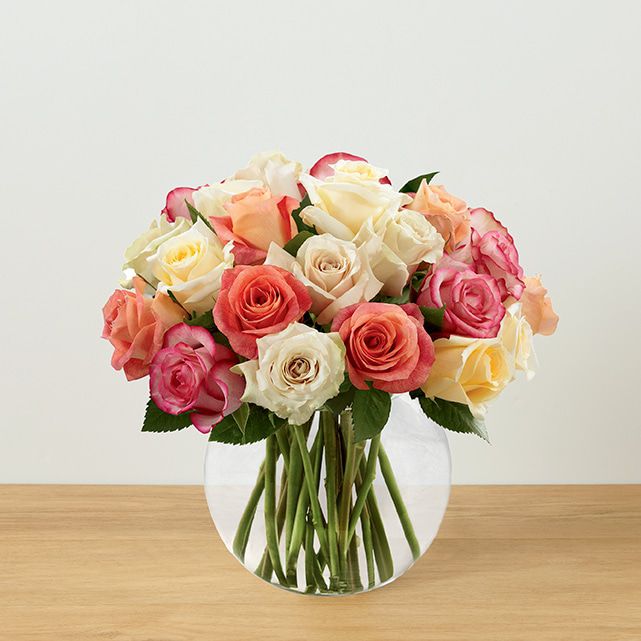 A clear vase arrangement with 24 colorful rose stems.