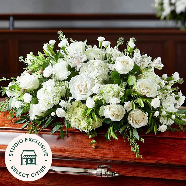 mixed casket spray in white with roses, hydrangeas, and lush greenery